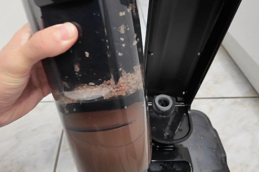 Der Wassertank vom Tineco Floor One S7 Stretch Steam Plus wird im Test herausgenommen und das aufgewischte dreckige Wasser wird ins Waschbecken entleert.